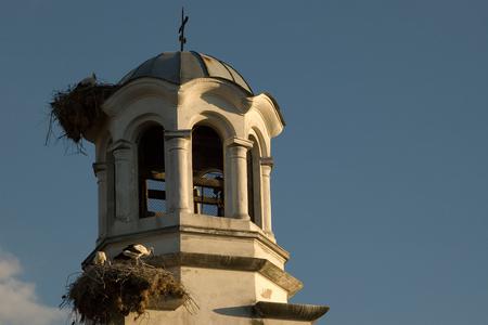 Zwei Storchennester und Störche auf dem Kirchturm der Kirche von Belozem in Bulgarien.