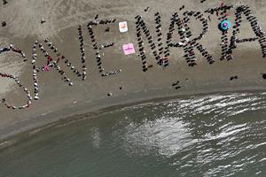 Menschen formen am Strand die Worte: Save Narta