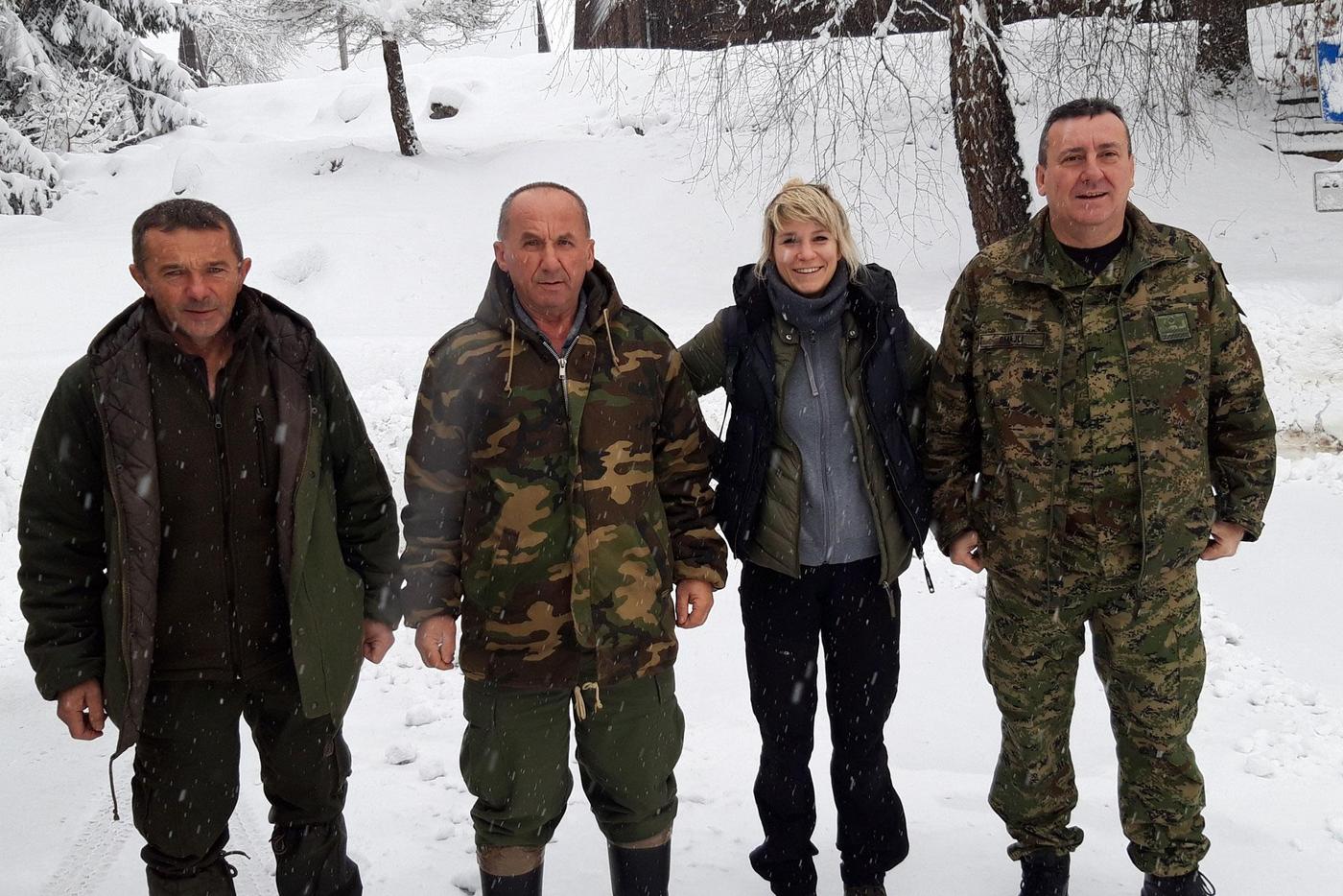 Ira Topličanec steht mit drei Jägern im Schnee.