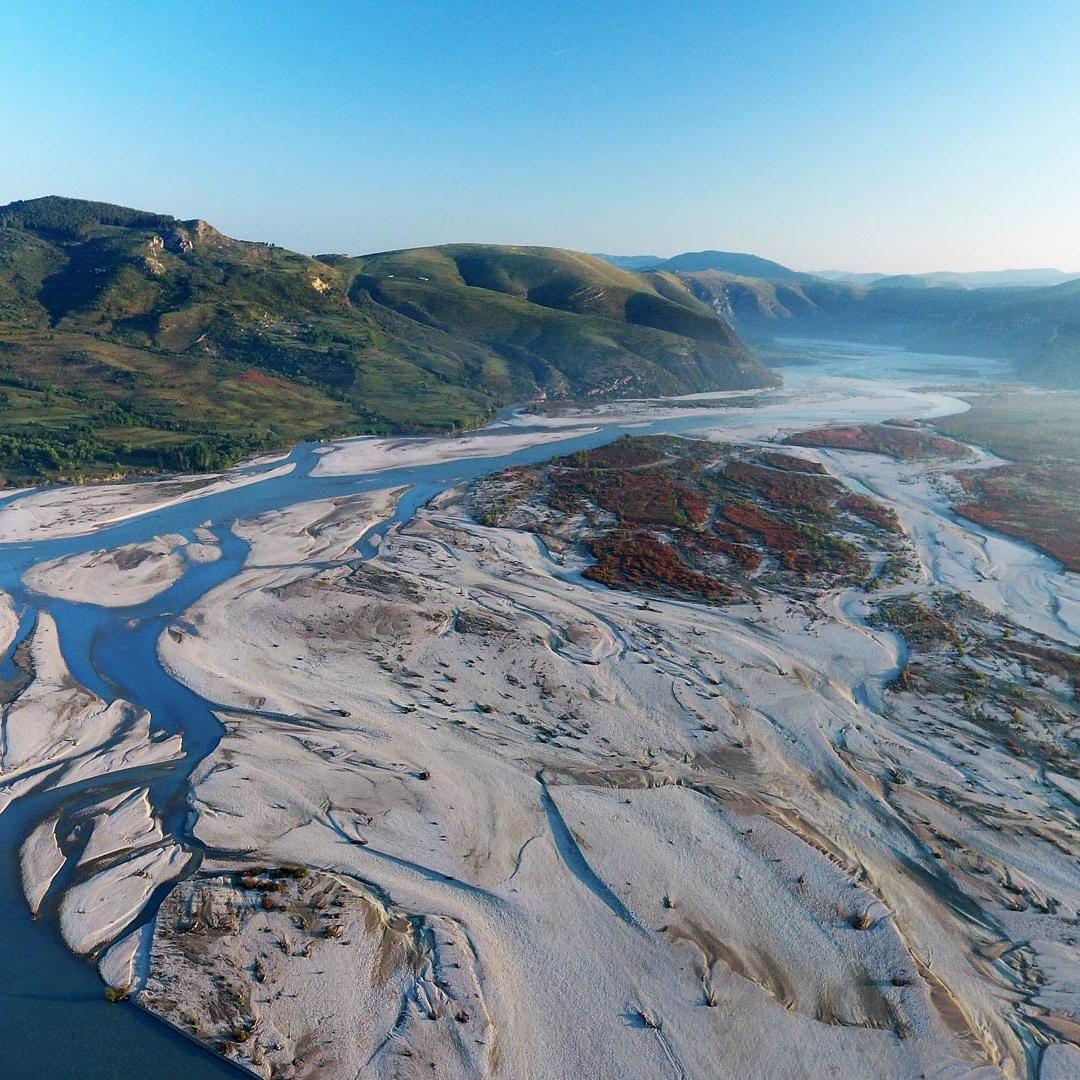 The wild river Vjosa with its natural riverbanks flows through a wide valley