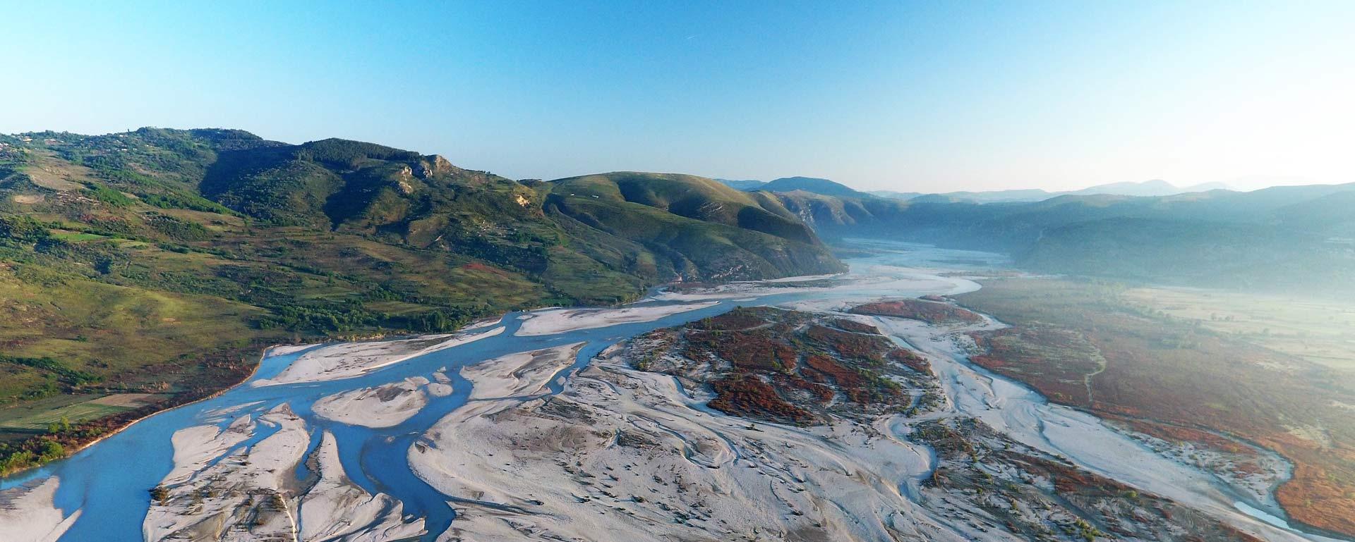 The wild river Vjosa with its natural riverbanks flows through a wide valley