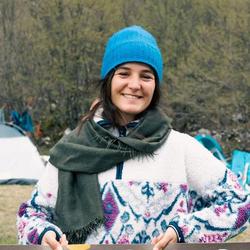 Jelena Popovic stands in front of the tent camp holding a banner.