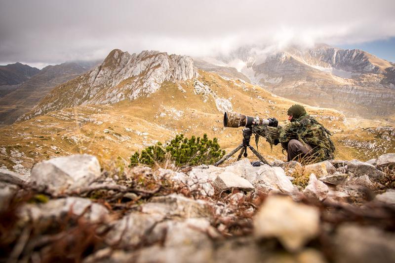 junger Fotograf im Tarnanzug in den Bergen