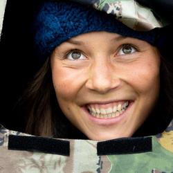 young nature photographer smiles out of the camouflage tent