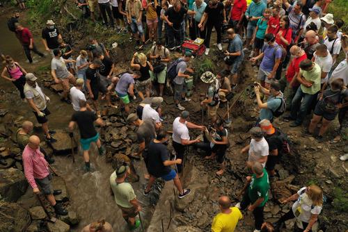 Beschädigung von Kraftwerkspipeline Viele Menschen mit Hacken und Schaufeln am und im Bach