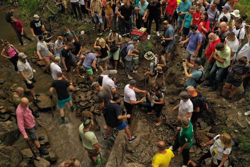 Many people with picks and shovels in and by a creek