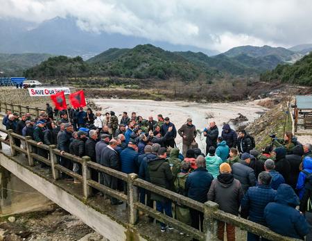 People with Albanian flags and megaphones stand on a bridge during a protest by mayors and residents of the Shushica Valley.