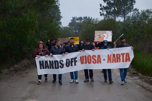 Demonstrierende mit Banner in der Narta-Lagune an einem Regentag