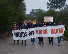 Demonstrierende mit Banner in der Narta-Lagune an einem Regentag
