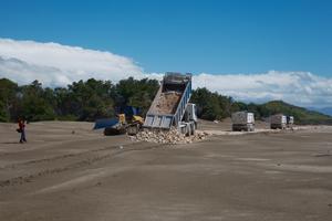 Lorries are unloading stones on the beach