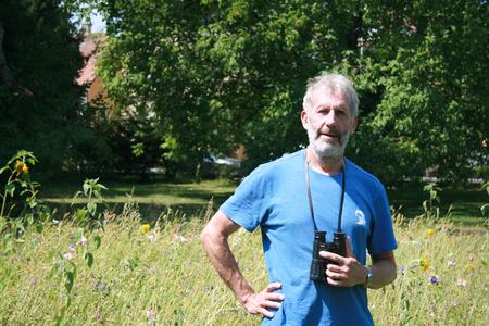 Mann mit Fernglas im Garten