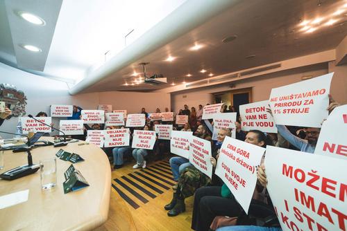 Komarnica Protest Protest performance during public debate on the Komarnica hydropower project in Podgorica, with placards stating "We don't destroy nature for 1% of electricity", "Killing a river is not development" and "Water is life, not profit."