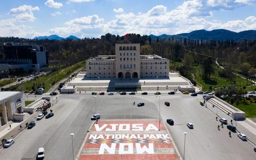 "Vjosa national park now" written in tall letters on the square in front of the university of Tirana