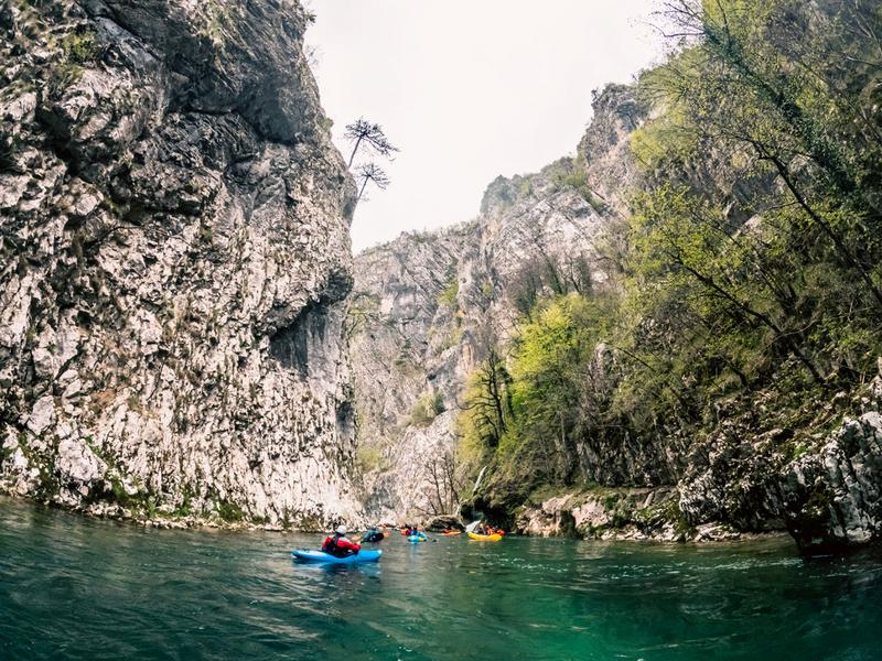 Eine Gruppe von Paddlern fährt mit ihren Kajaks auf der Komarnica durch eine Klamm.