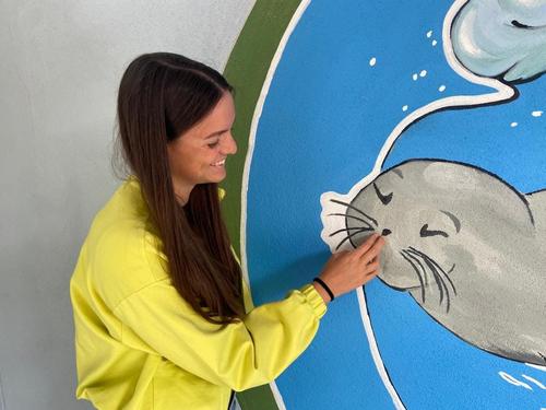 Dina Levačić in front of a mural Dina Levačić and a painted seal