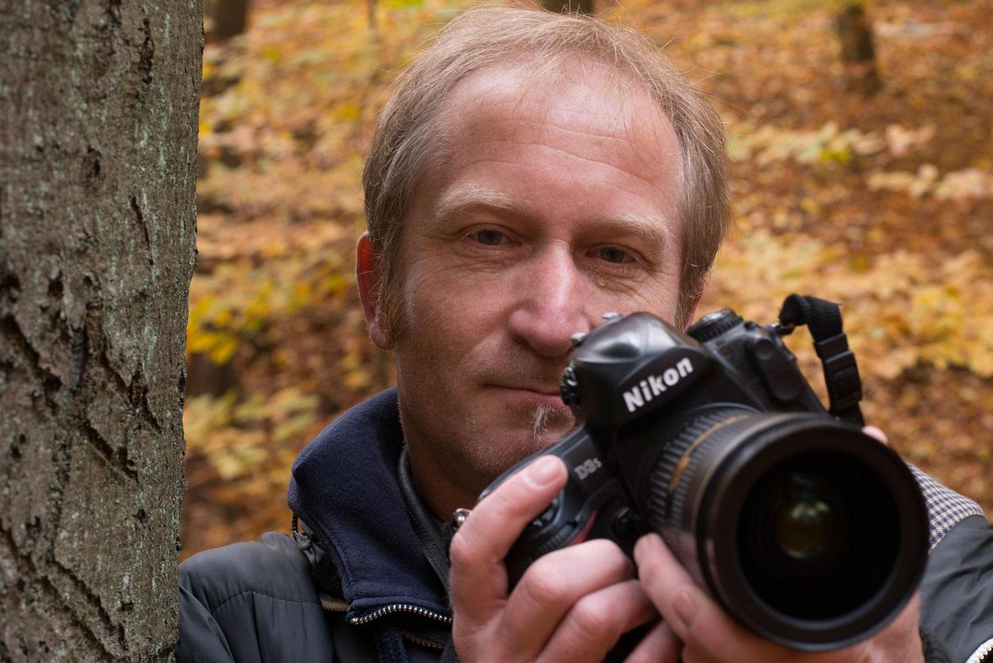 man next to a tree with a camera