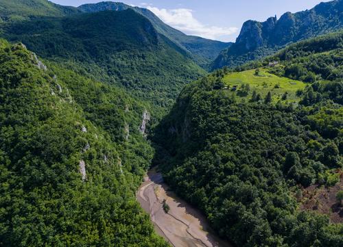 Der Fluss Janjina fließt zwischen bewaldeten Hängen.