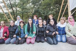 The Brave Women of Kruscica kneel close together on a bridge.