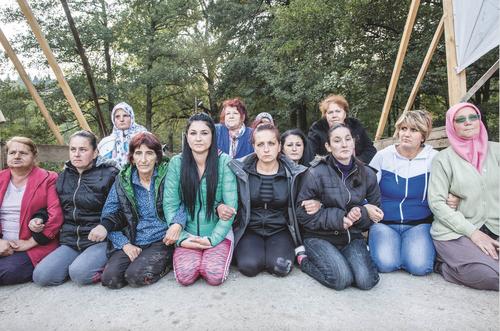 Women sitting on a bridge blocking the road