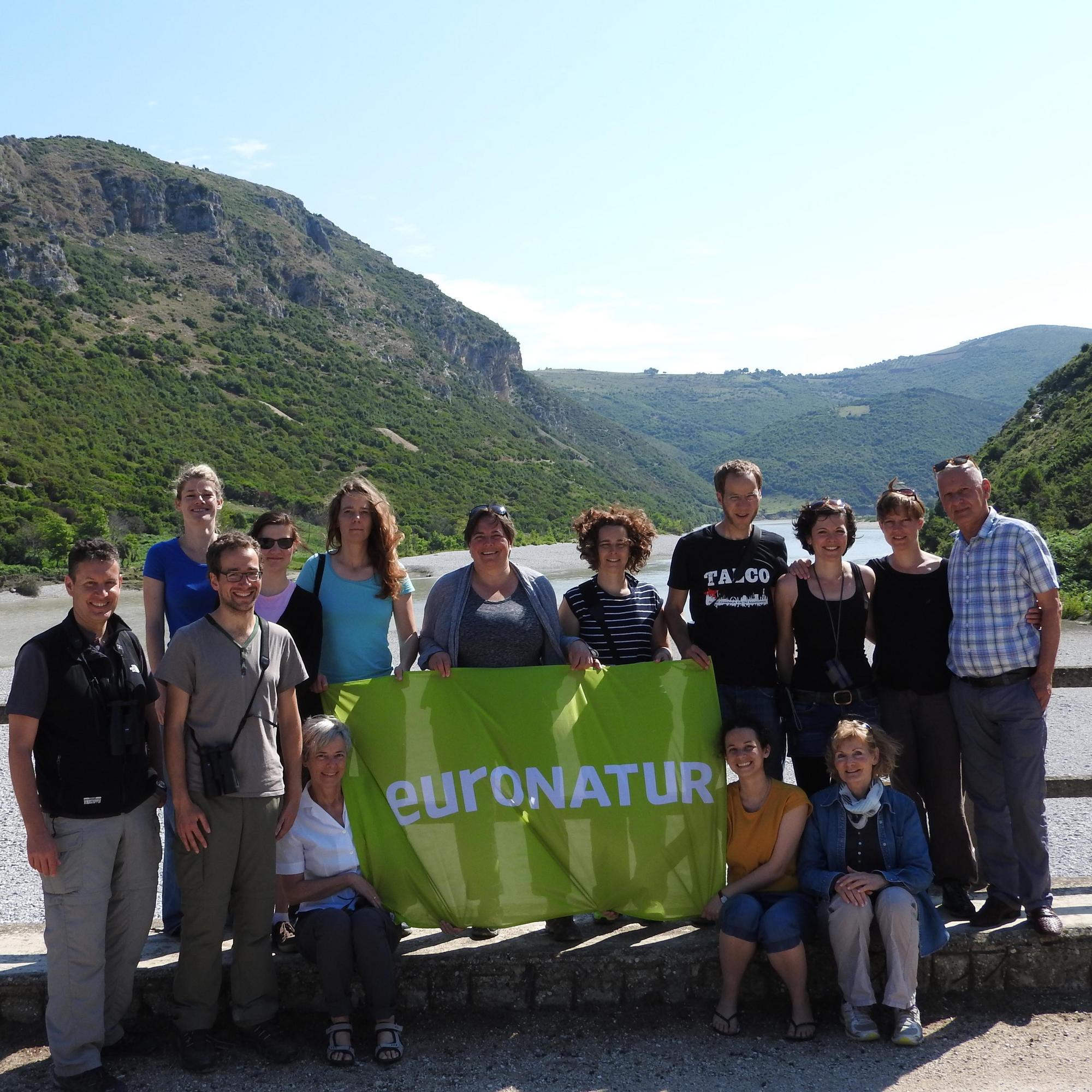 EuroNatur staff with EuroNatur flag in front of a river