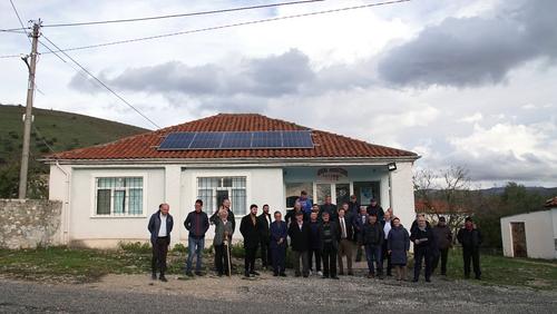 People from Kutë in front of a building with solar panels