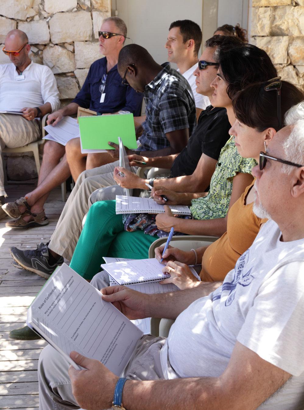 People with writing materials sit on a terrace at Mava Leaders Day.