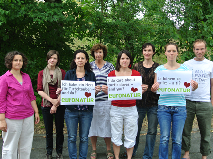 People with EuroNatur posters standing before a group of trees