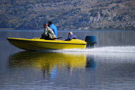 Drei Männer in einem Motorboot rasen über den See