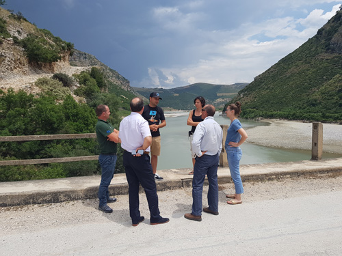 Sechs Menschen diskutieren auf einer Straße mit Blick auf die Vjosa