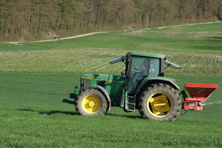 Traktor mit Düngerstreuer auf einem Feld